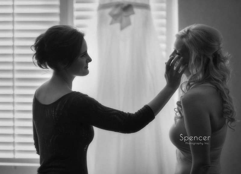 maid of honor wiping tear from brides cheek