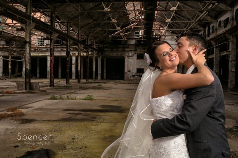 groom kissing bride in artistic wedding picture in warehouse in cleveland
