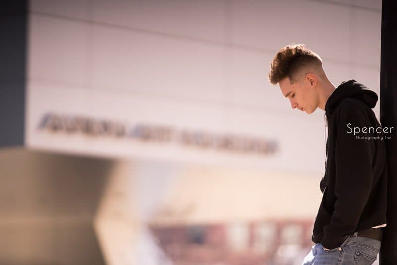high school senior looking at ground in front of Akron Art Museum