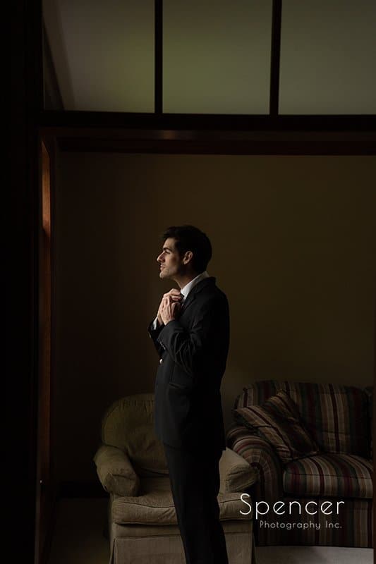 groom adjusting his wedding tux tie