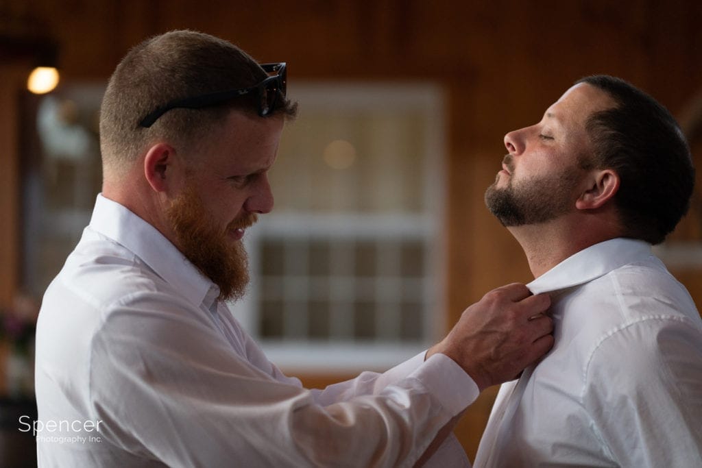 best man helping groom with tie
