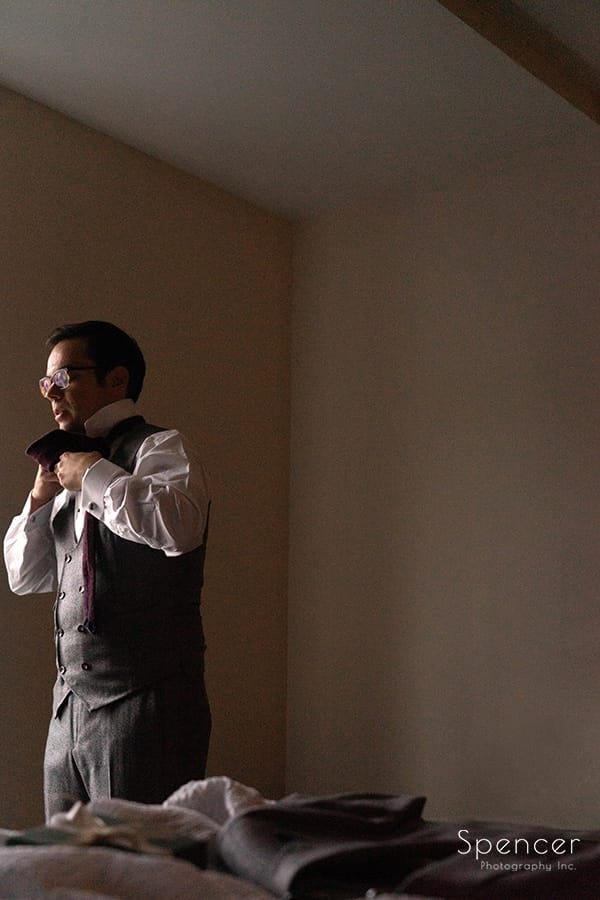 groom putting on wedding tie at Akron Marriott